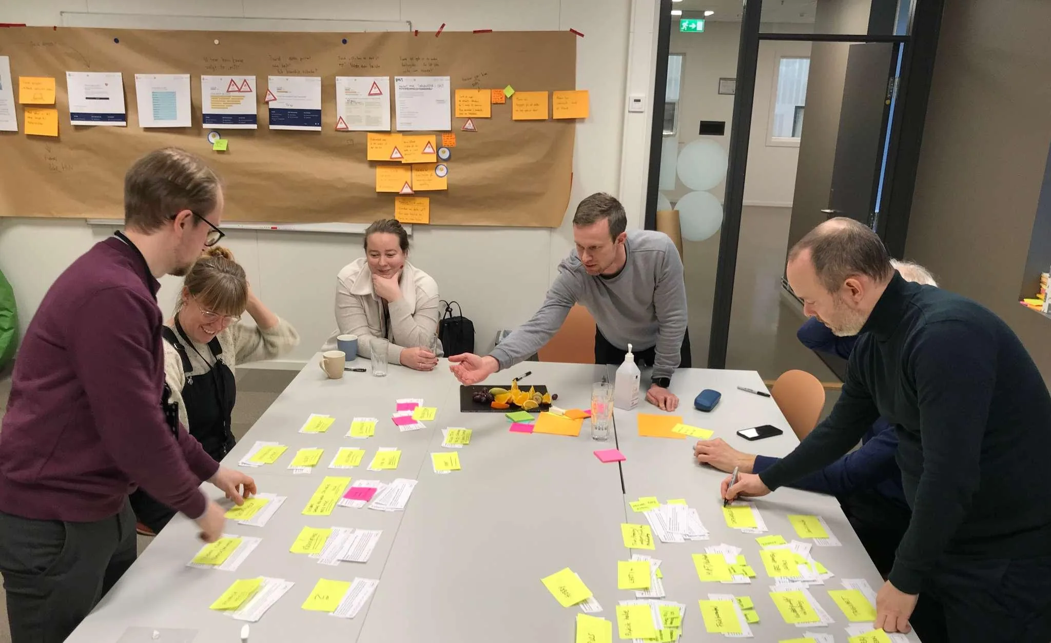 Cross-functional team collaborating around a whiteboard to map ideas, workflows and business strategy.