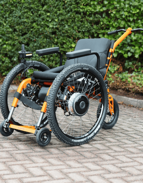 Orange SD Motion Trike with push handle, and joystick, side view