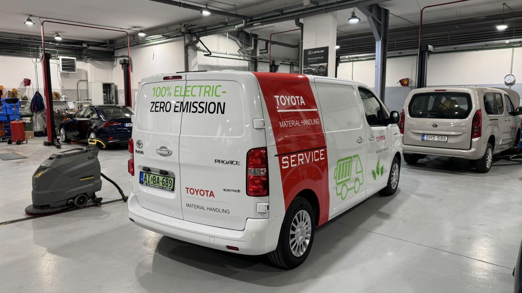 Fehér színű Toyota Proace elektromos furgon egyedi flottadizájn fóliázással. A járművön a Toyota Material Handling hivatalos piros és zöld céges dekorációja látható, amely tökéletes példája a minőségi céges autófóliázásnak és márkaépítésnek.