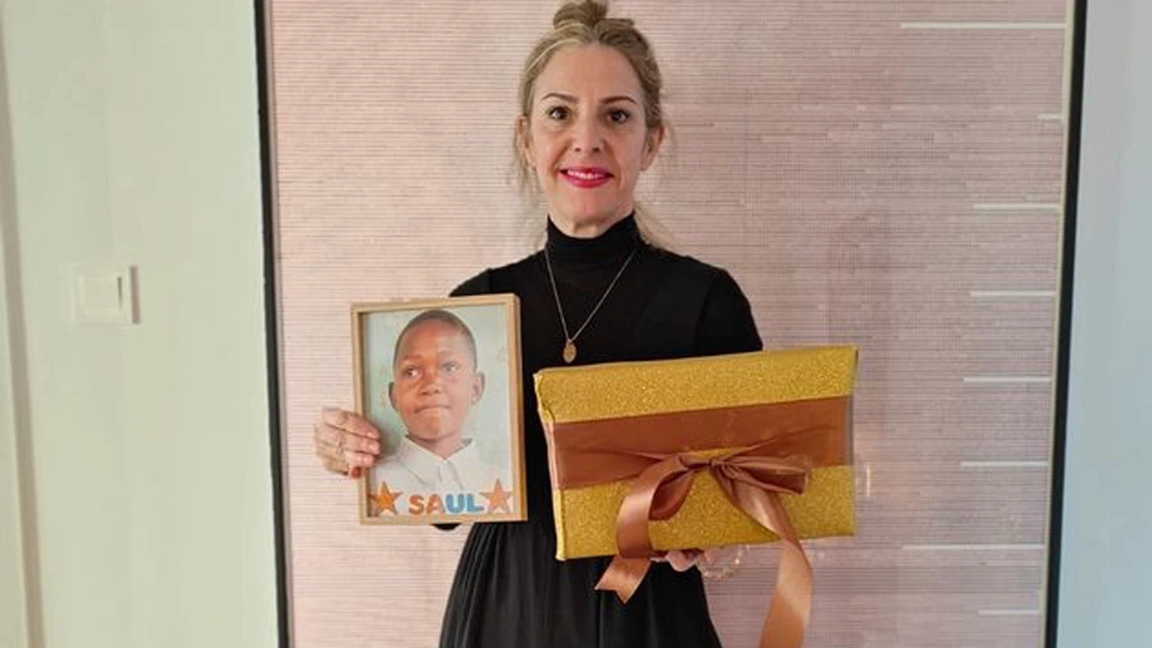 María sosteniendo la foto de Saúl y un regalo solidario