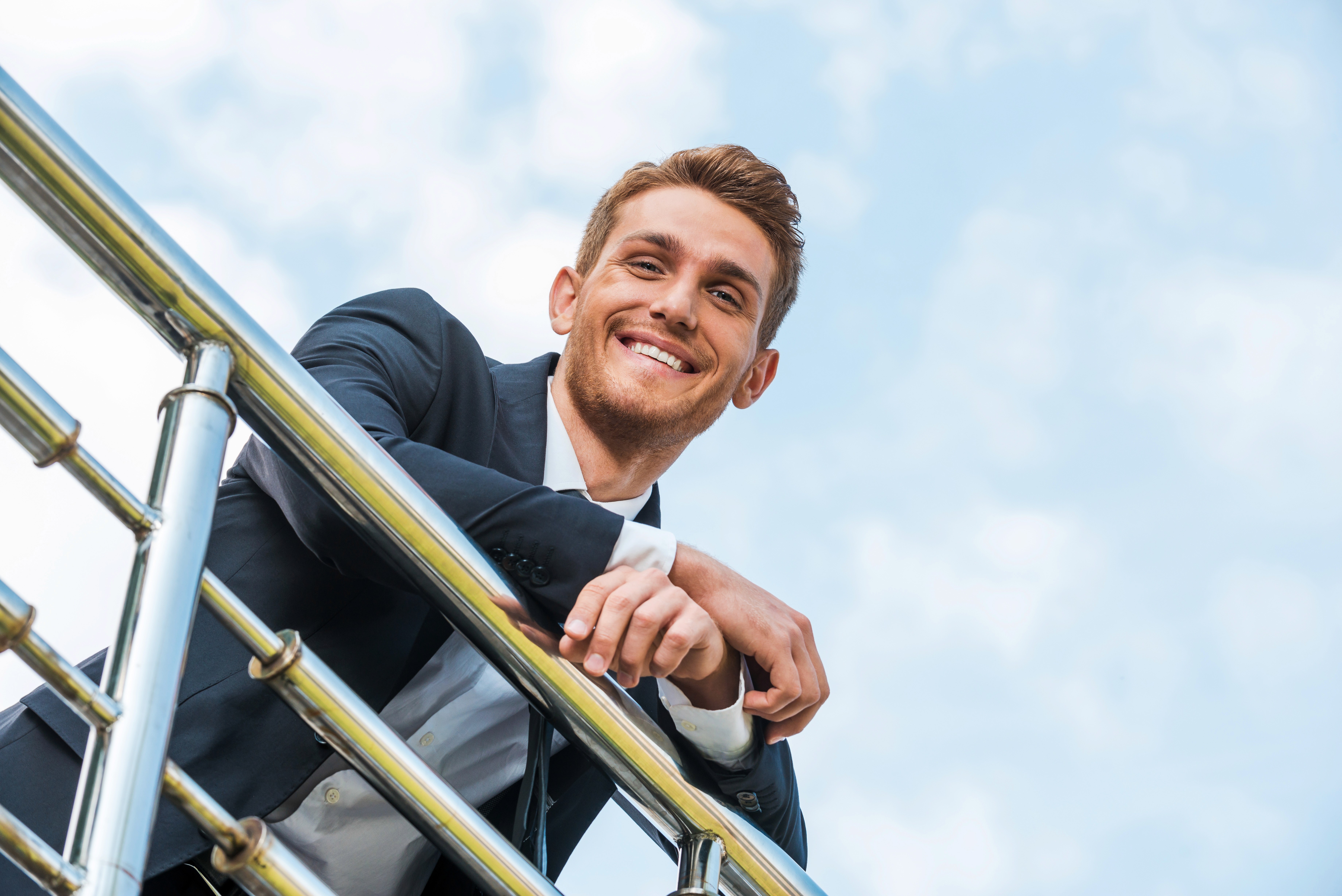 Flaga Unii Europejskiej z dwunastoma żółtymi gwiazdami na niebieskim tle, powiewająca na wietrze na tle częściowo zachmurzonego nieba.