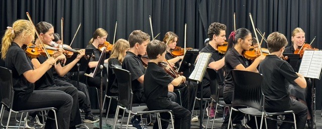 Cairns String Orchestra students preparing with conductor before a live performance in community hall