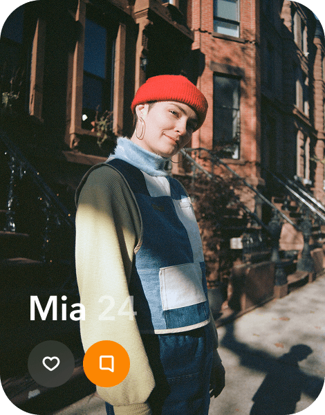 a profile of a young person in a fleece jacket and red beanie in front of a brownstone's stoop