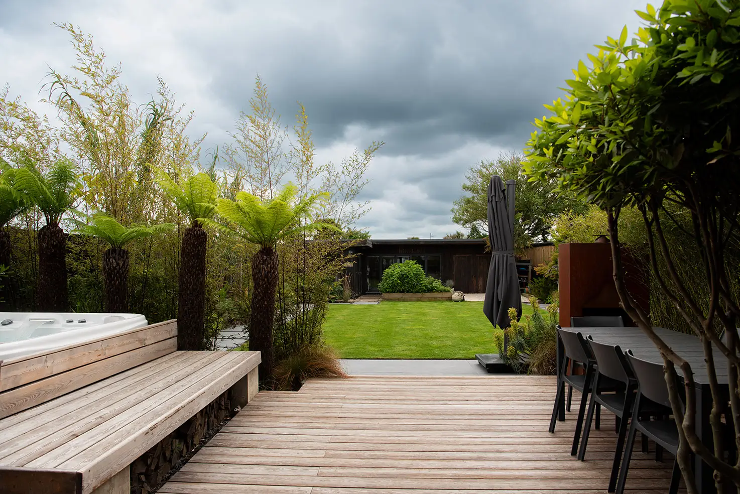 A garden scene with wooden steps leading to a lush green lawn under a cloudy sky.