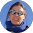 Woman wearing glasses and a blue jacket, smiling warmly.