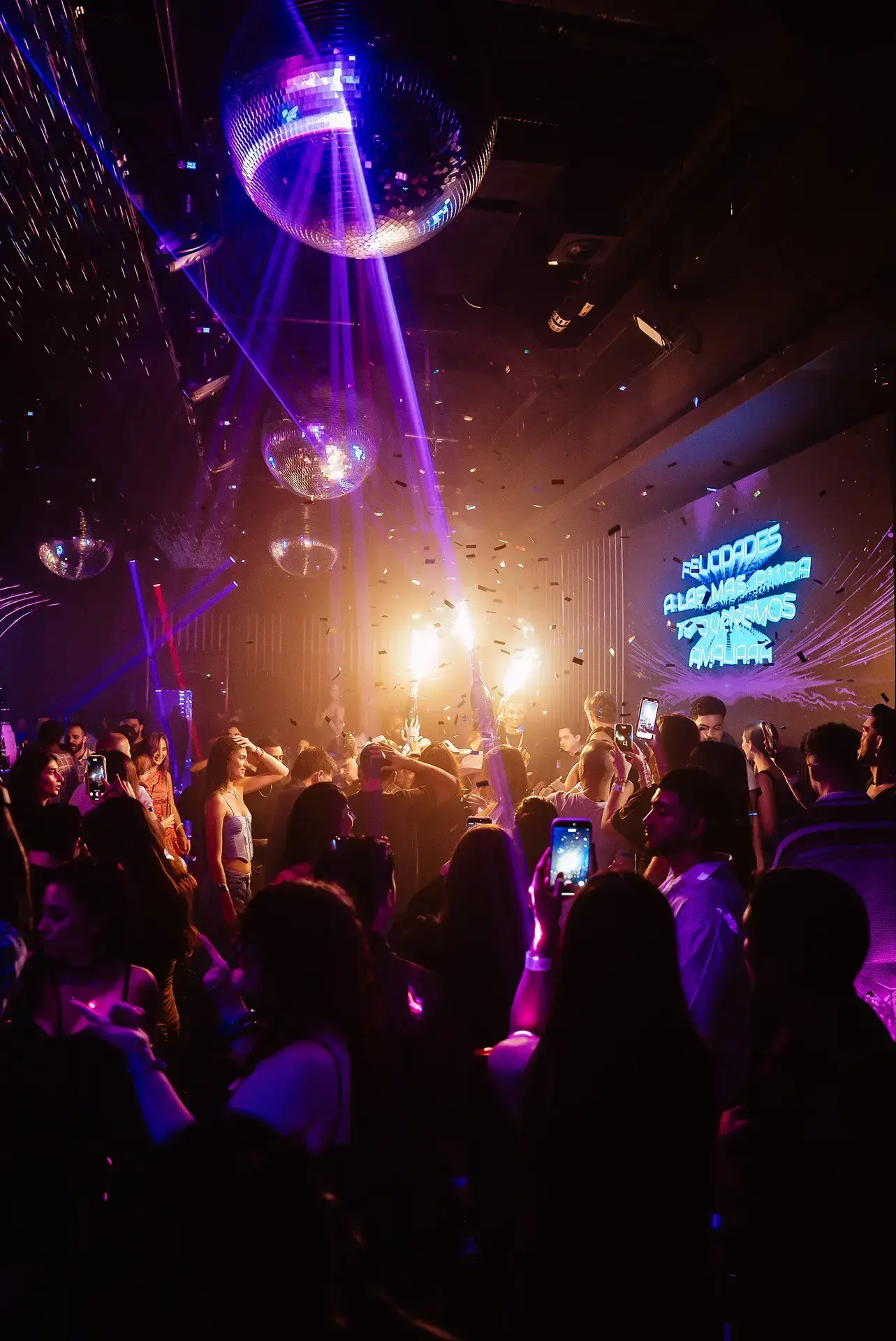 Crowd celebrating under disco balls with sparklers and confetti at The Myth Dubai