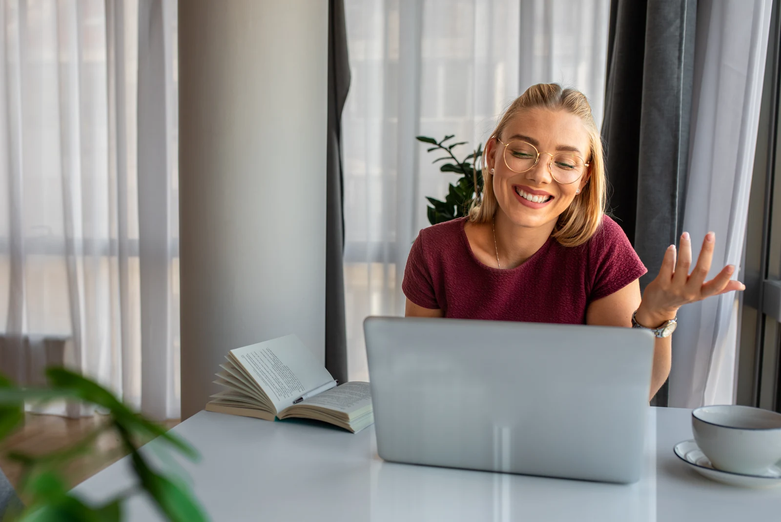 Smiling woman talking with someone on her laptop from a bright home workspace