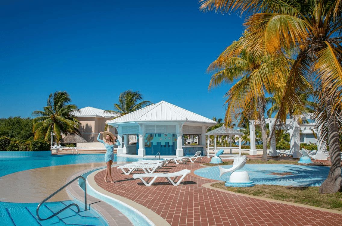 Series of luxury tropical resort layouts featuring turquoise swimming pools, palm trees, and modern poolside cabanas under a clear blue sky.