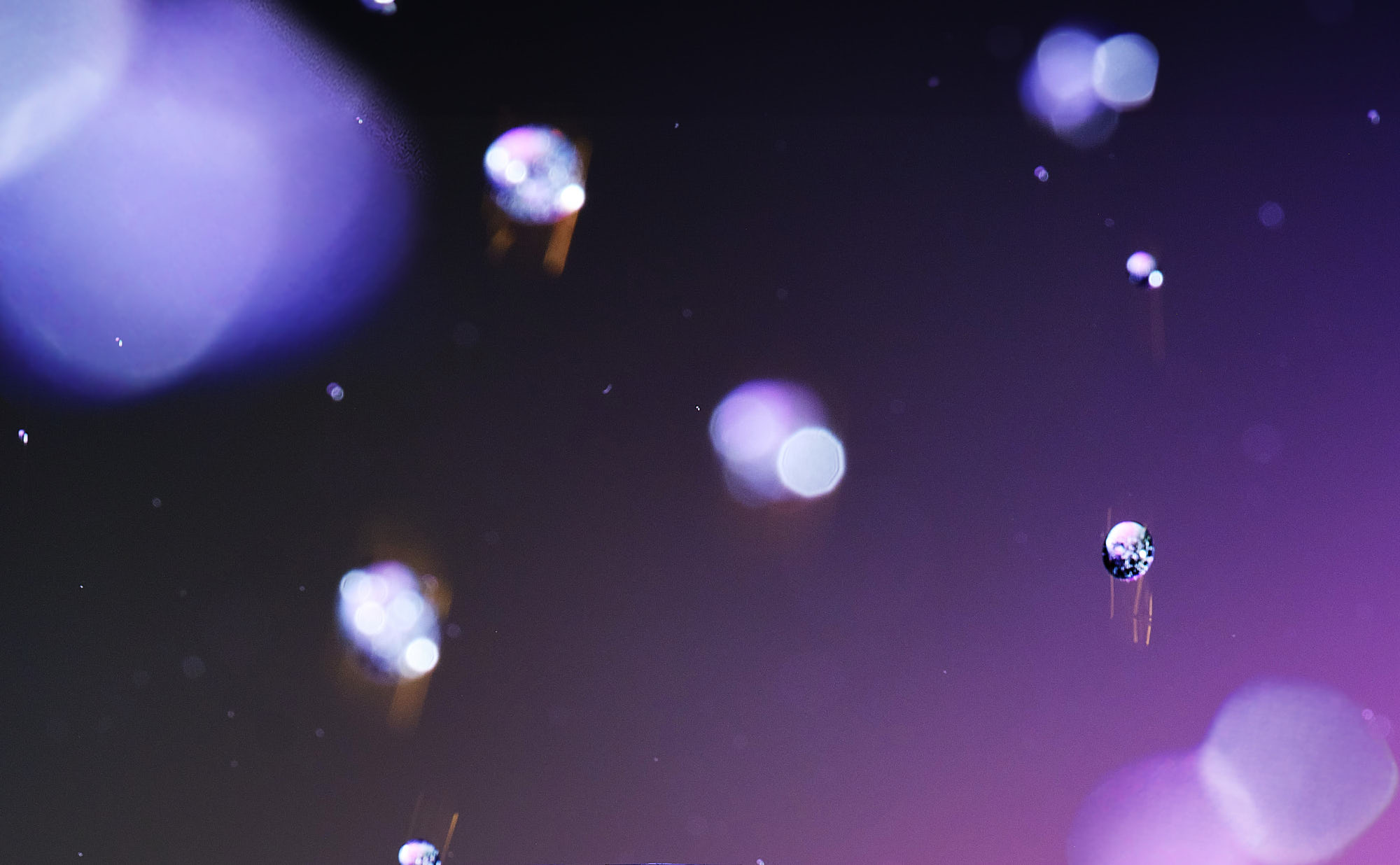 Abstract background featuring soft, glowing orbs in shades of purple and blue against a dark backdrop.