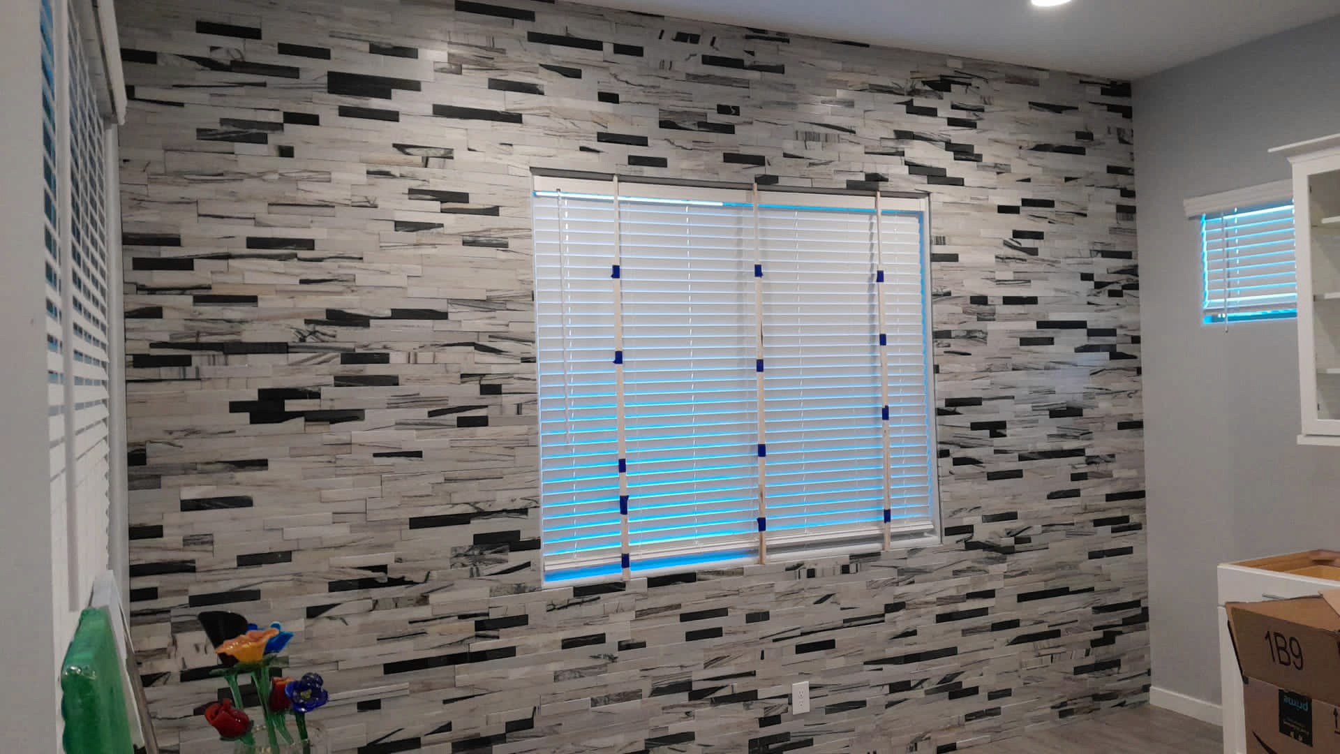 Modern room with a black and white striped tile wall and a window with horizontal blinds.