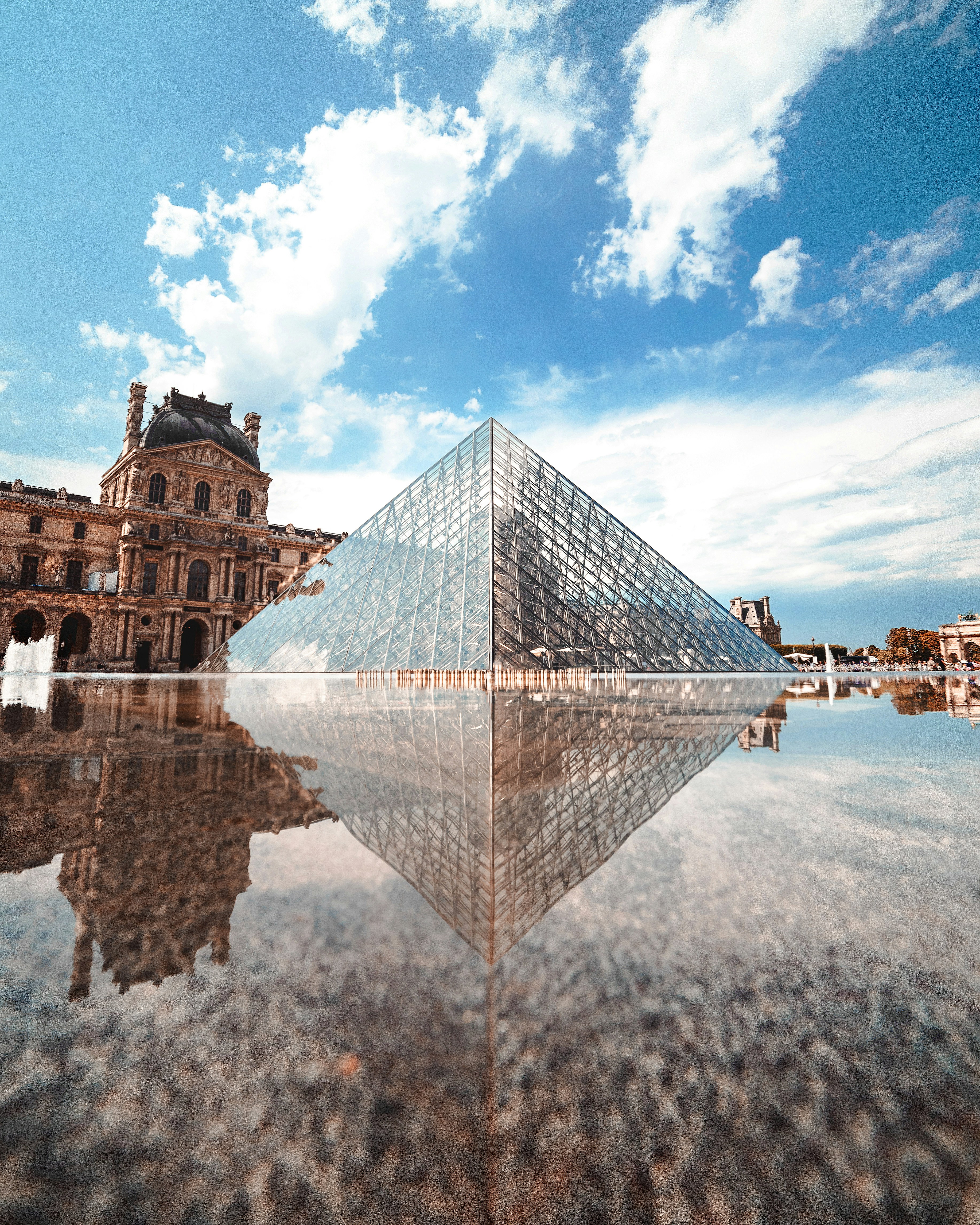 glass pyramid building near body of water during daytime