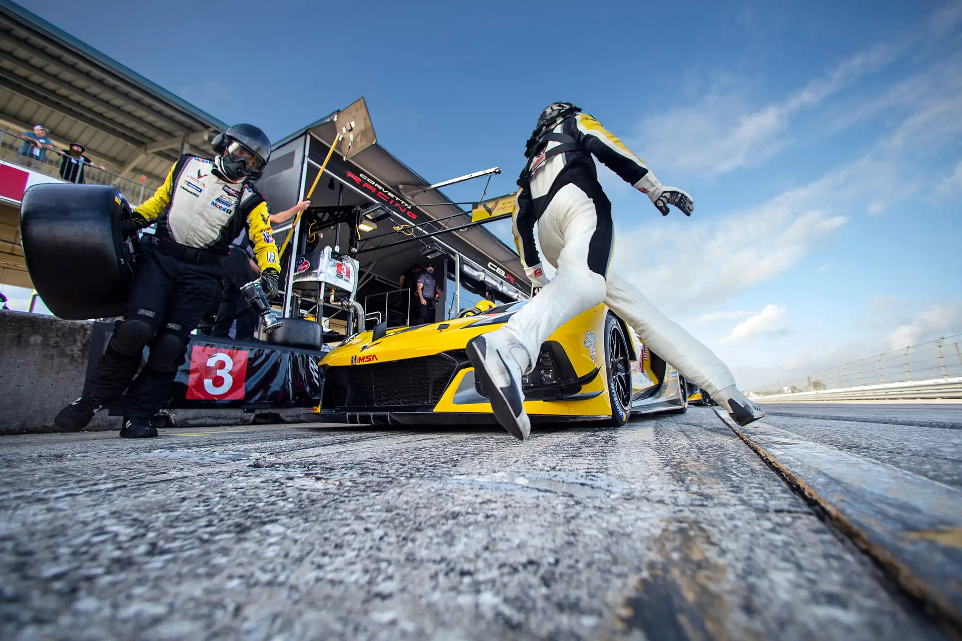 A yellow racecar making a pit stop.