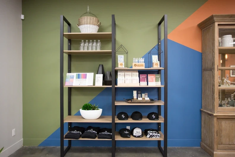 Kannabis Works display shelf with curated products against a backdrop of green and blue walls.