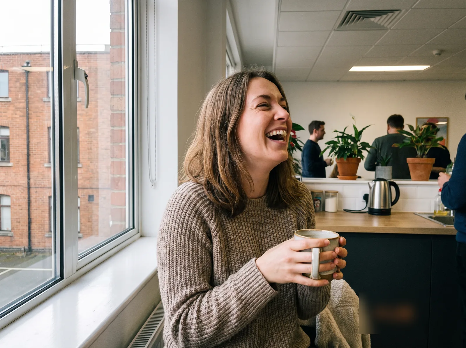 Sophie laughing with a mug of tea at work