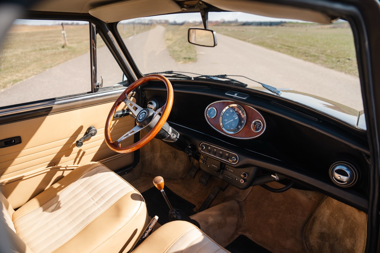 Classic car interior featuring a wooden steering wheel and retro dashboard with gauges.