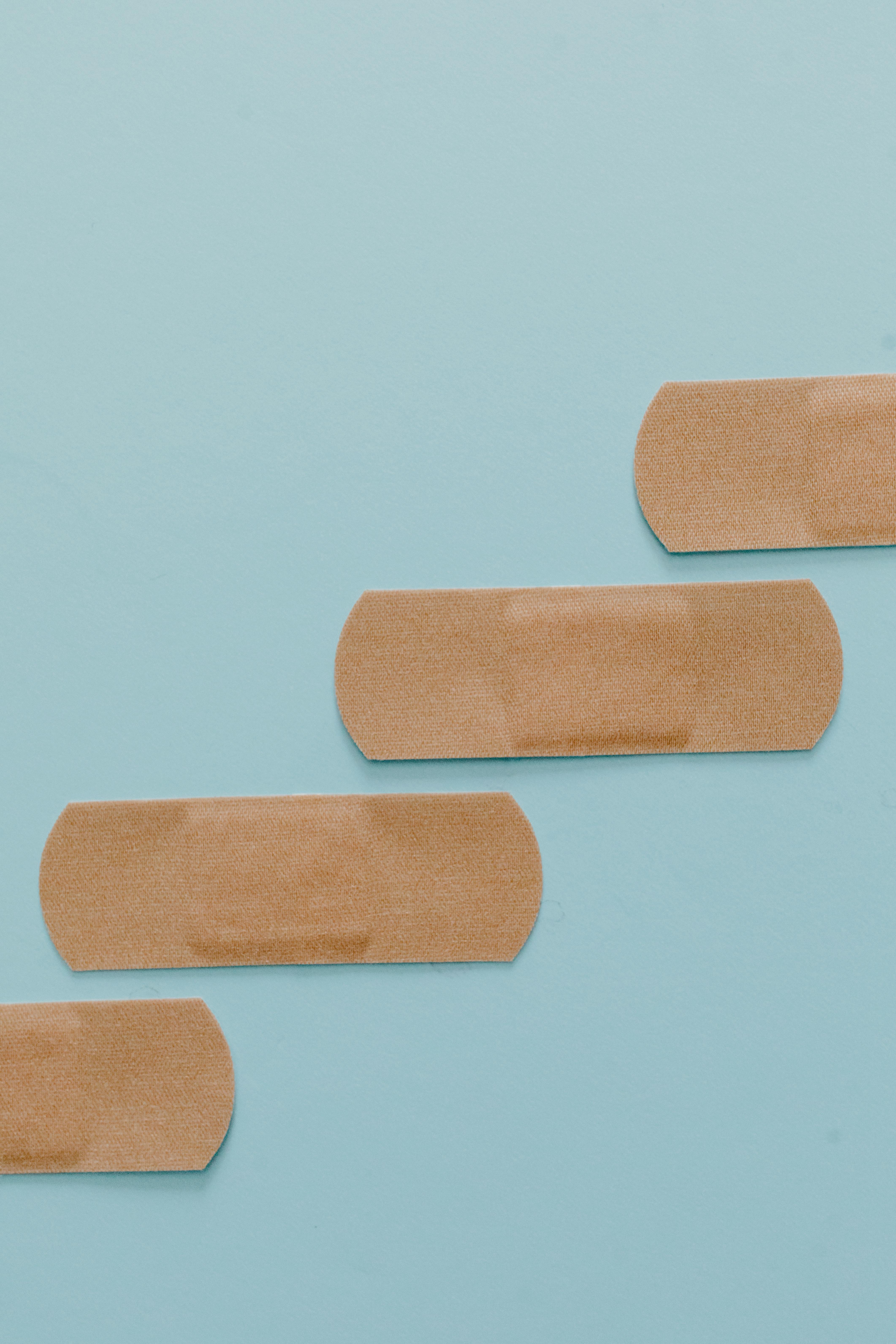Three beige adhesive bandages on blue background