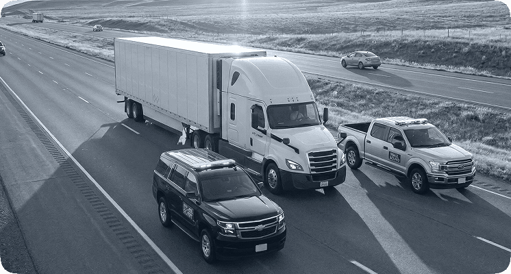Semi‑truck passing passenger car on highway near warehouses representing trucking safety and traffic risk