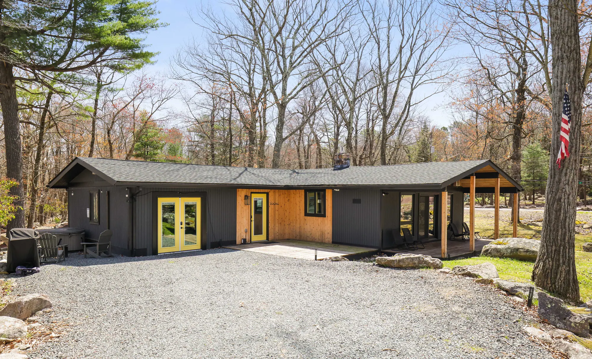 Black ranch cabin with yellow doors and gravel driveway at The Love Shack, Lake Harmony, PA