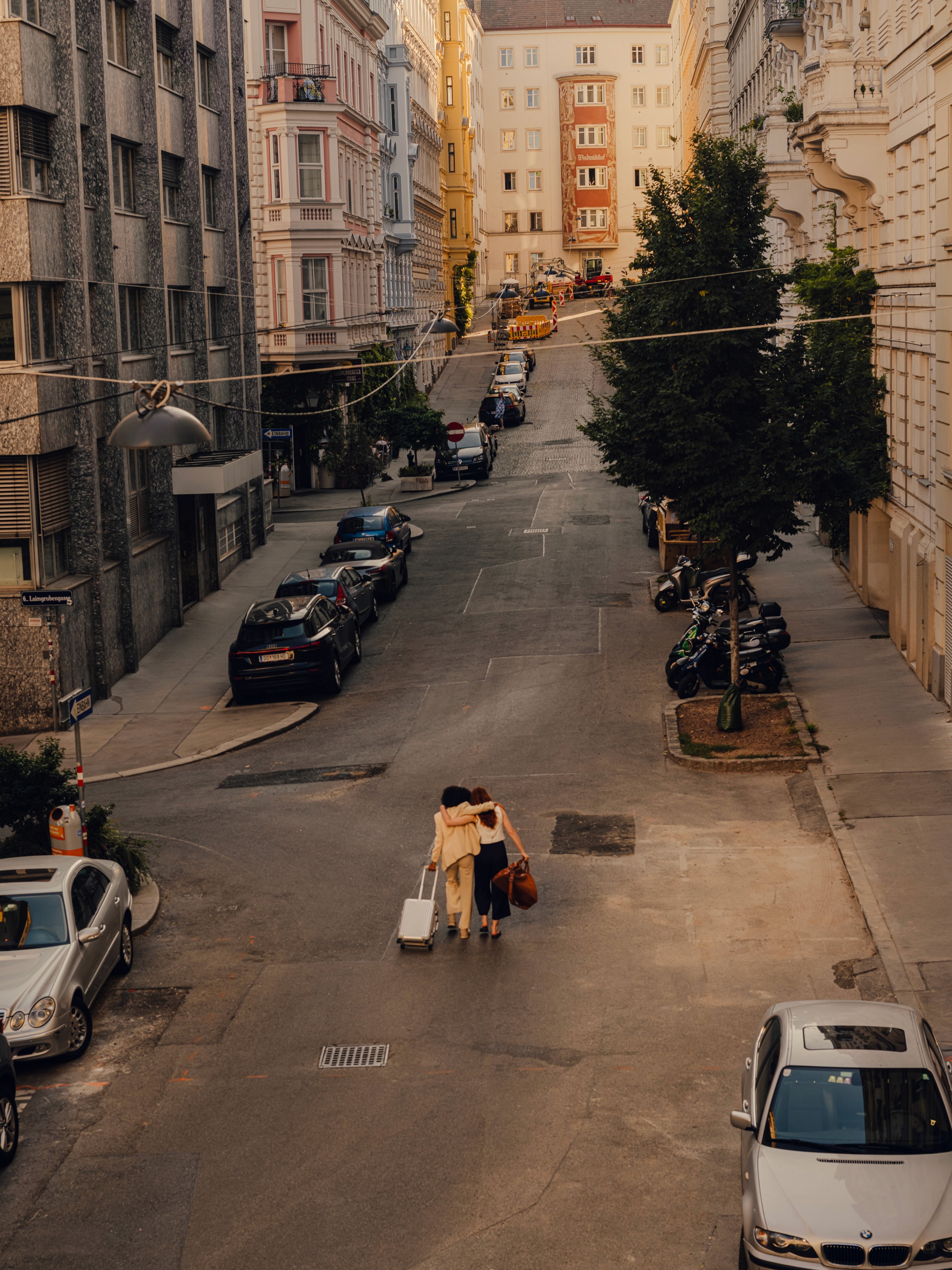Two people walking with their luggage in Vienna's streets.