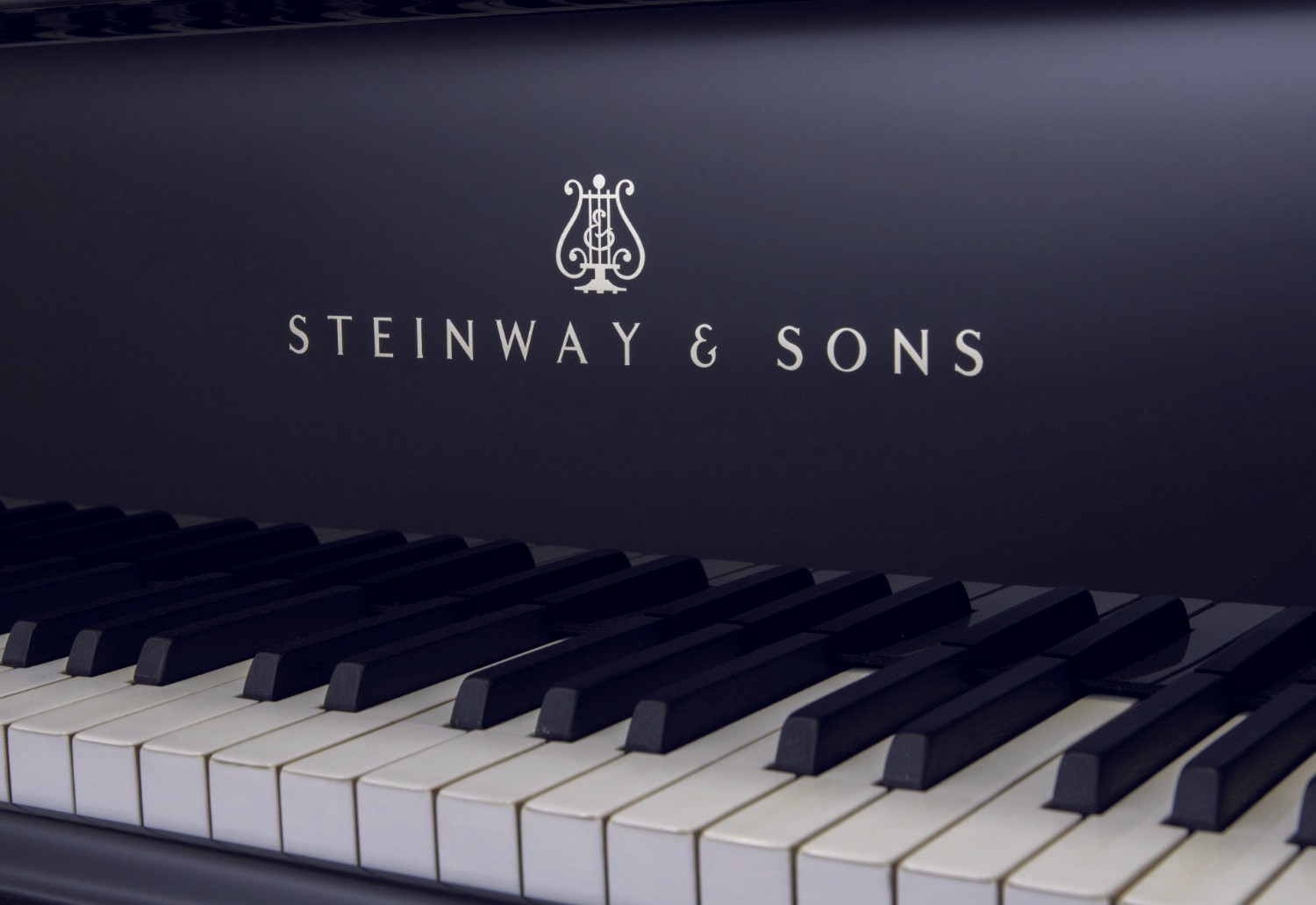 A close-up of the Steinway & Sons logo on the fallboard, with the keyboard in focus, emphasizing the fine details of the restoration.