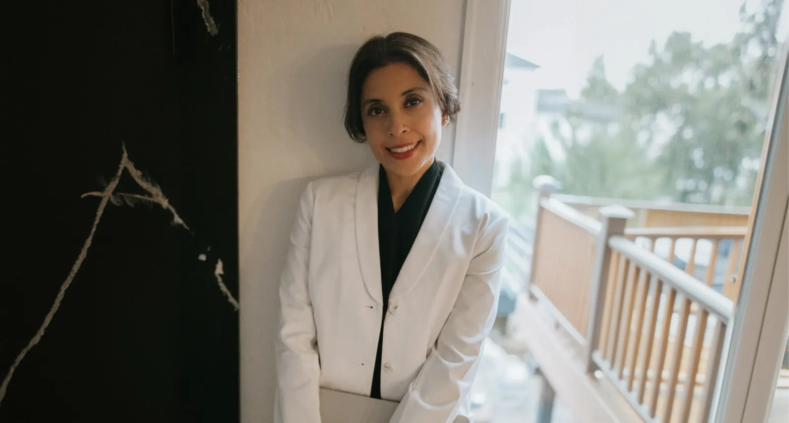 Dr. Maryam Sheikh in a white blazer by a window