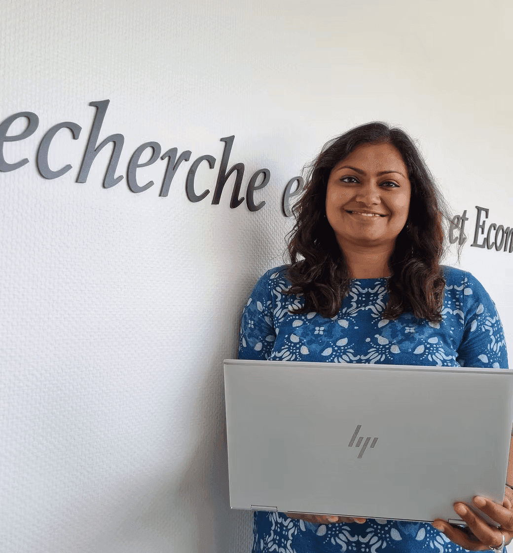 Portrait of a researcher holding a laptop in front of university name board