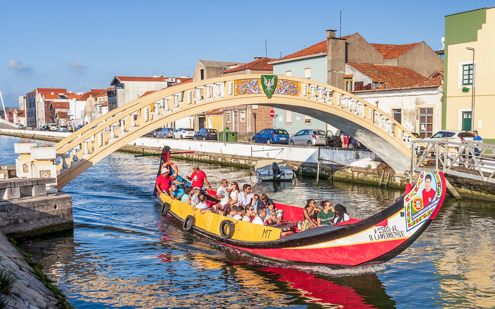 Moliceiro boat tour under bridge in Aveiro canal, Portugal.