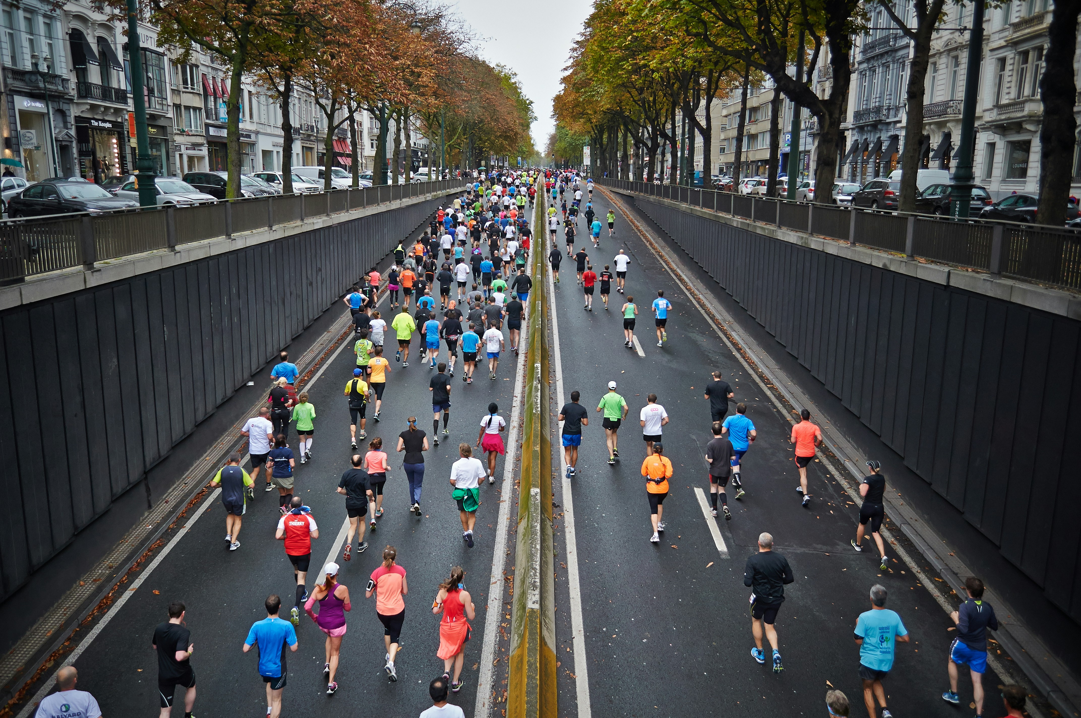 A Picture of People Running a Marathon Through A Big City Avenue