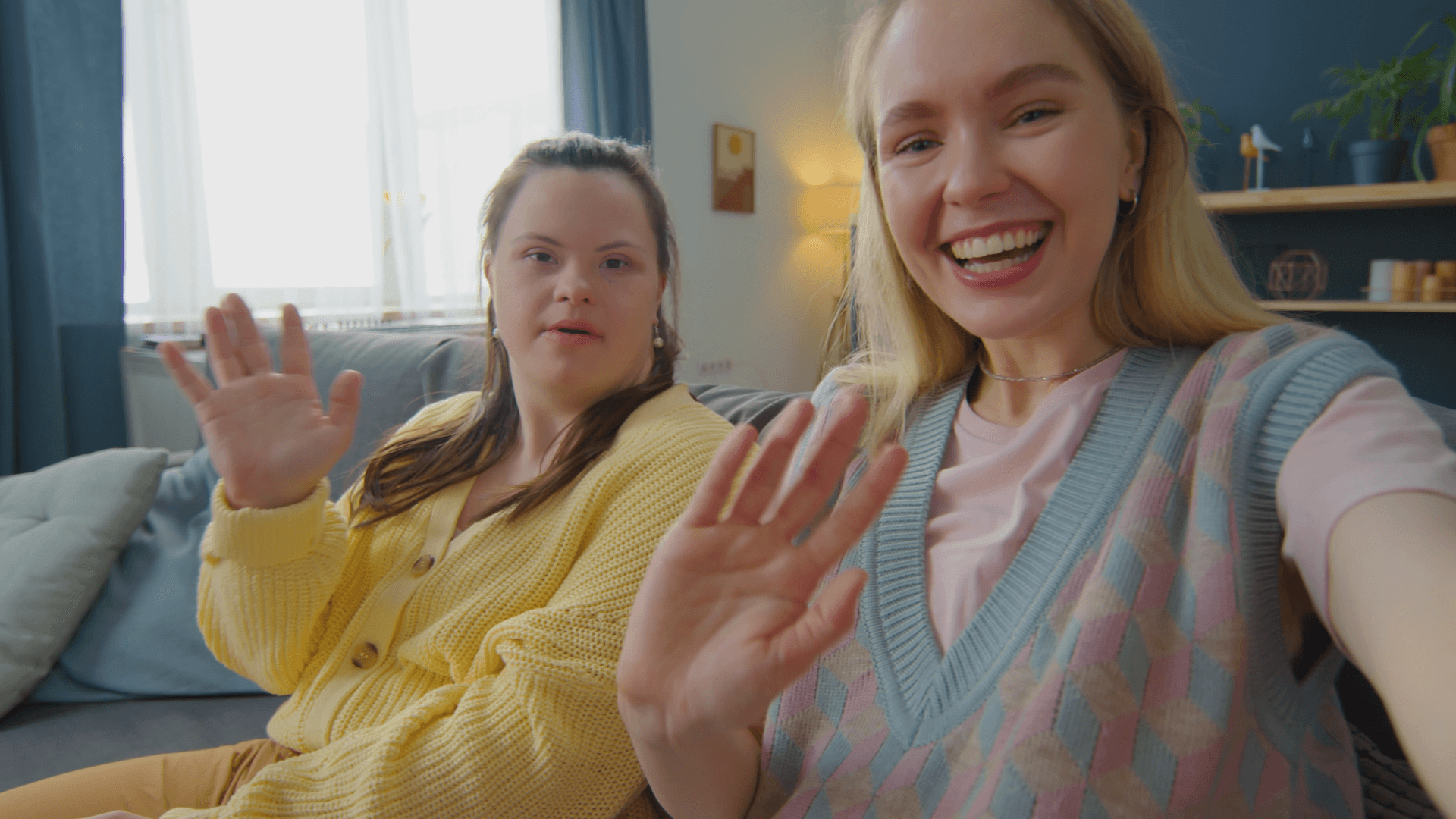 Two women waving for a photo.