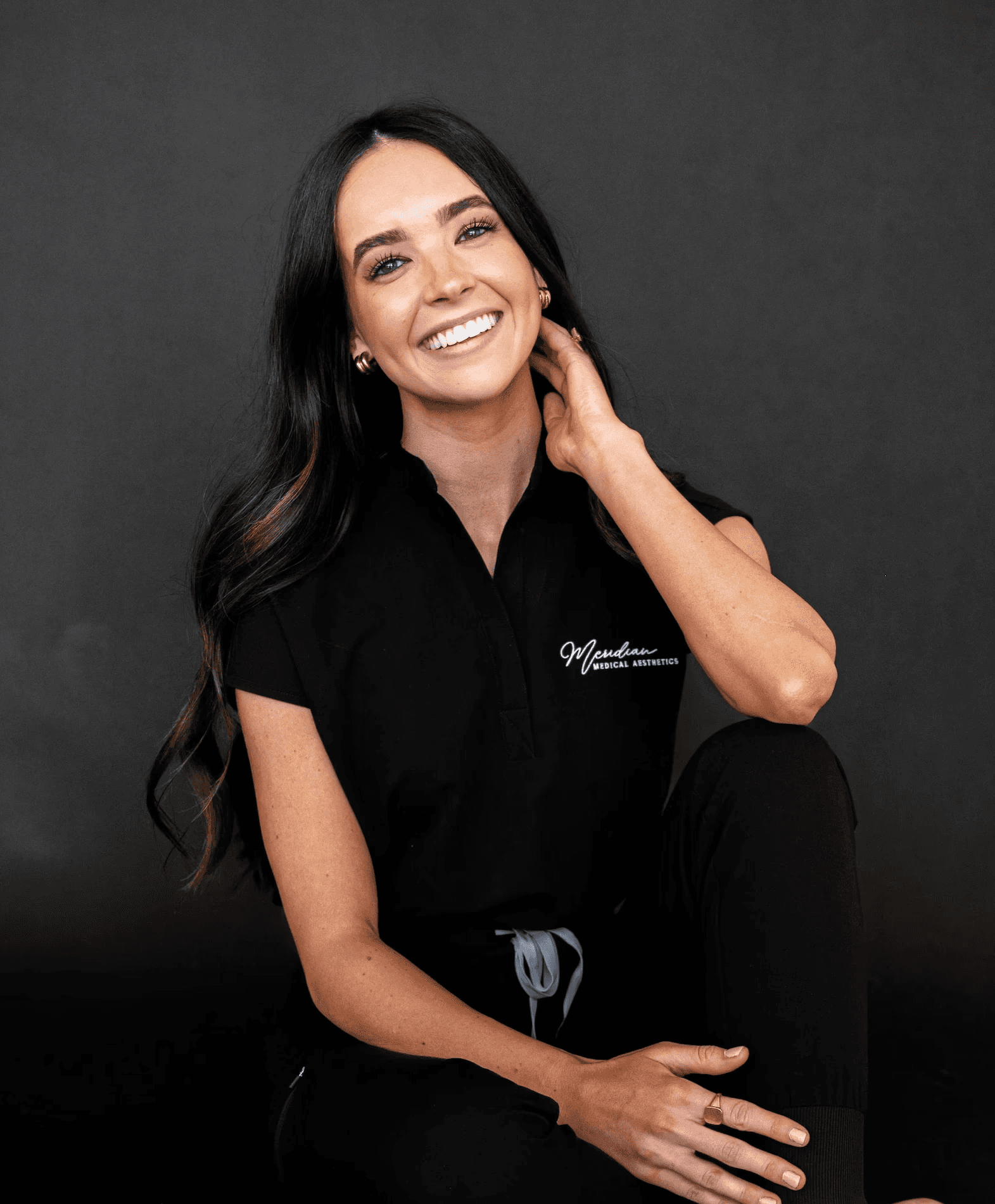 Portrait of Nurse Practitioner Melinda O’Neal smiling outdoors in blue medical scrubs, Meridian Medical Aesthetics.