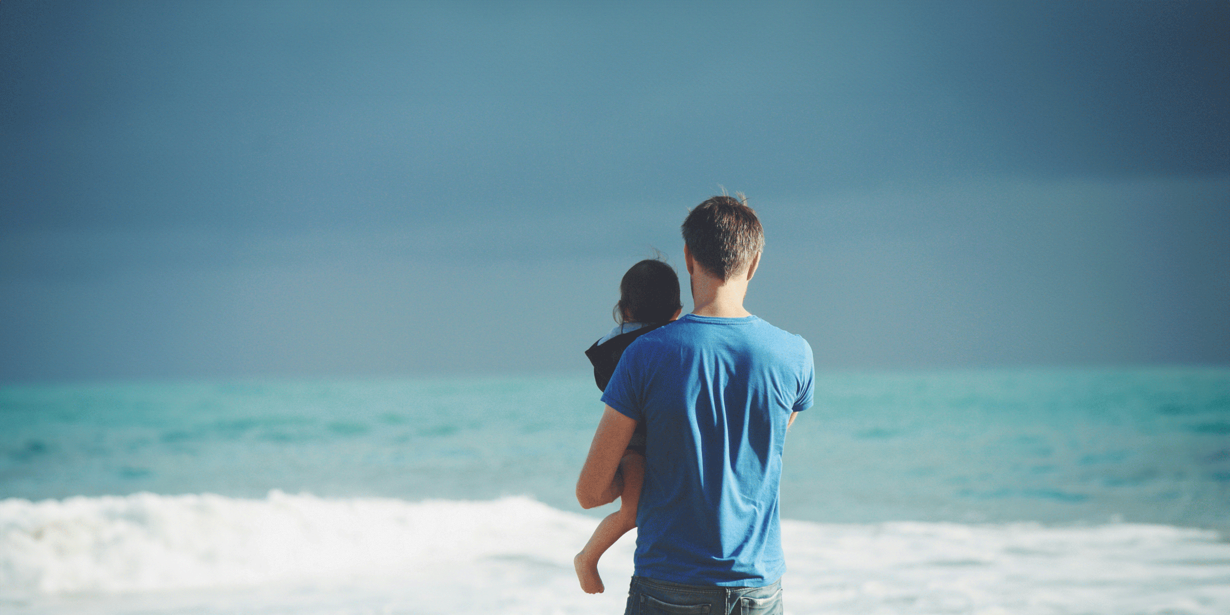 image of father holding child by the ocean