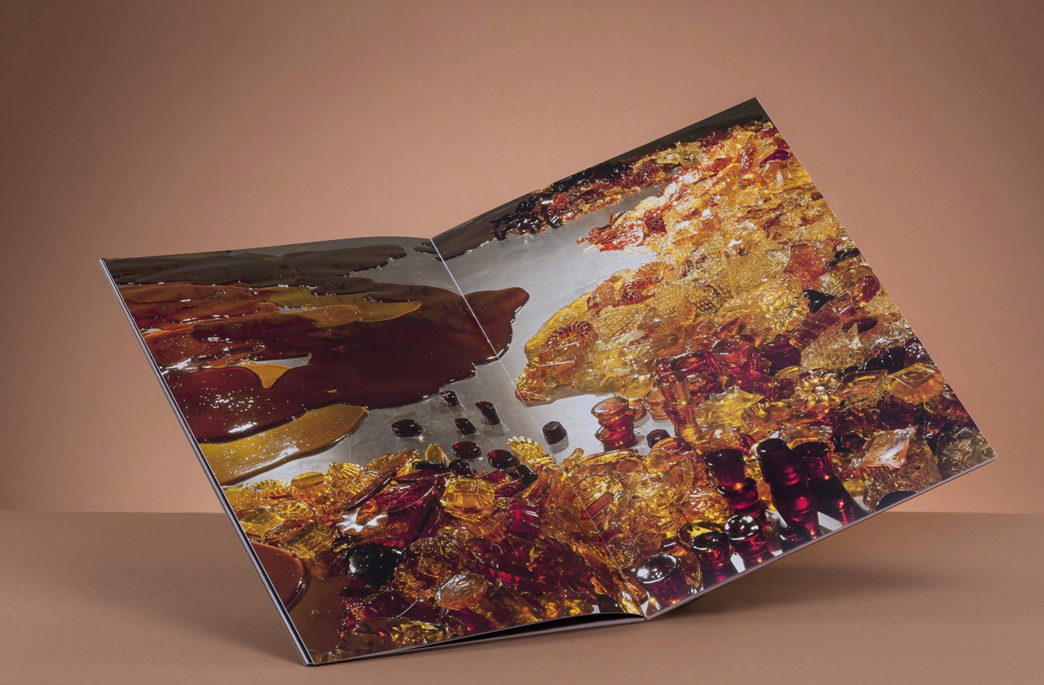 A close-up of an open book showcasing vibrant, colorful amber materials on a reflective surface.