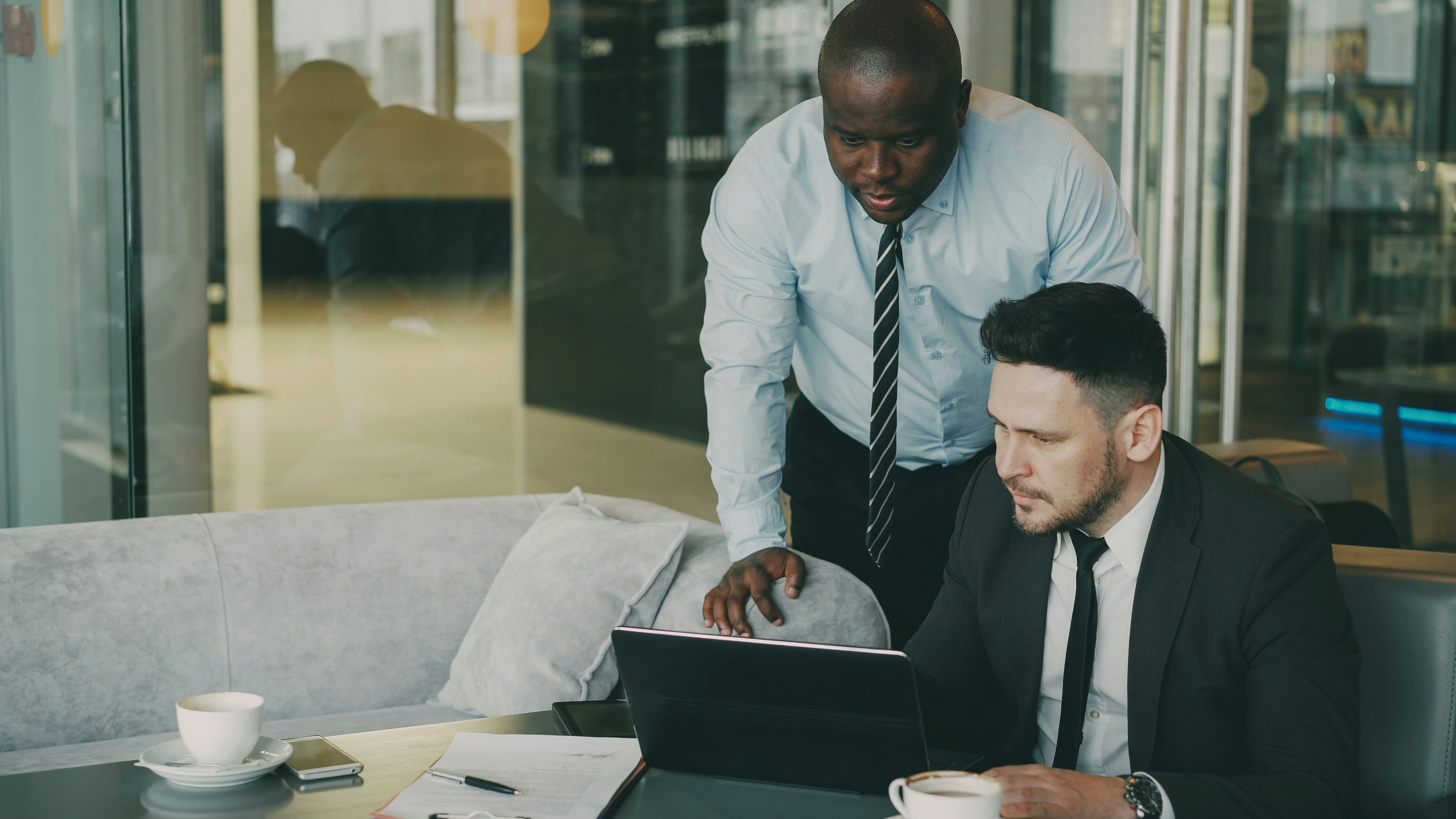 Two businessmen collaborating on a laptop in a modern office.