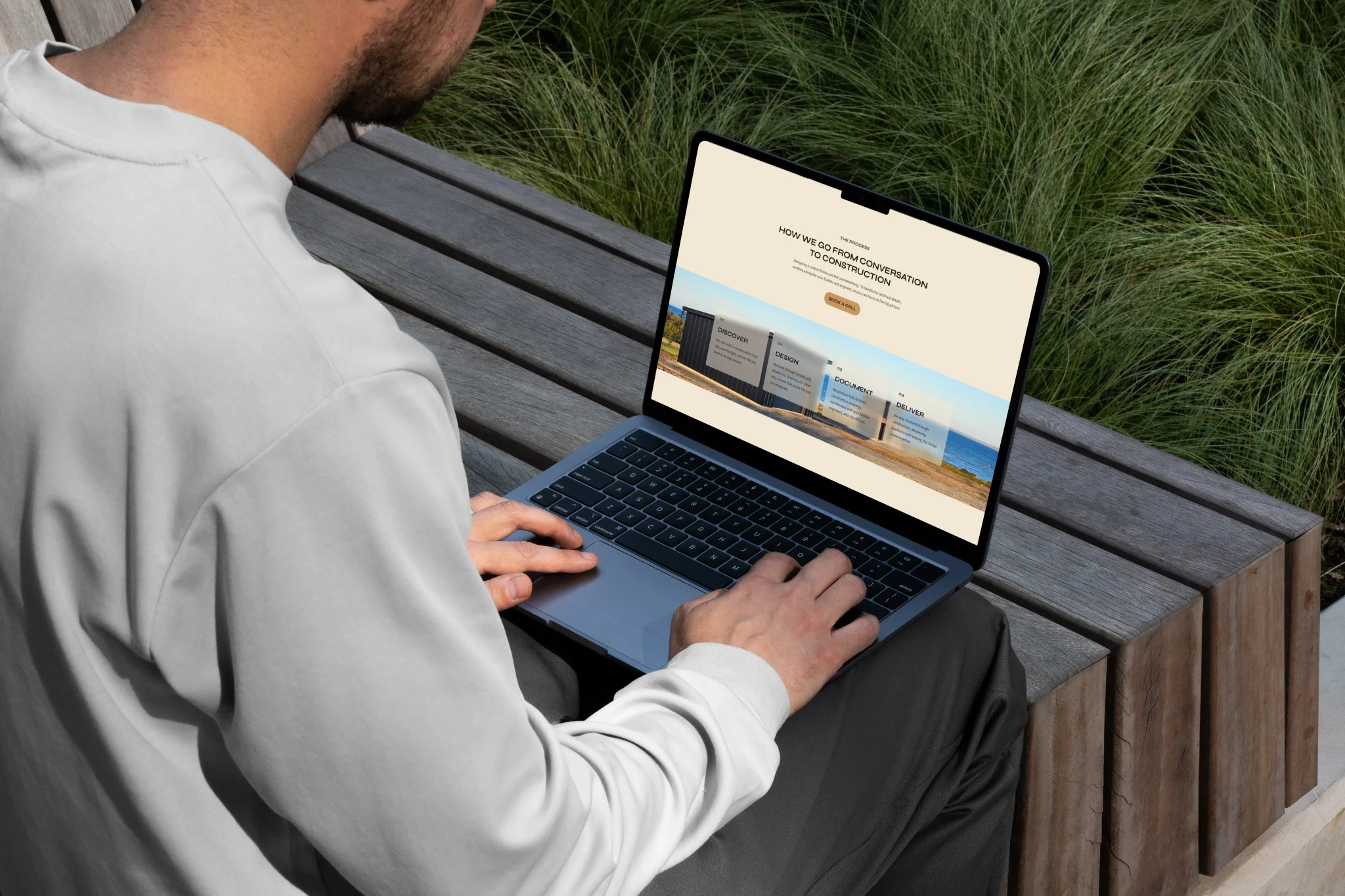 Laptop on a person's lap showing the KW Building Design "process" section outlining Discover, Design, Document, and Deliver steps.