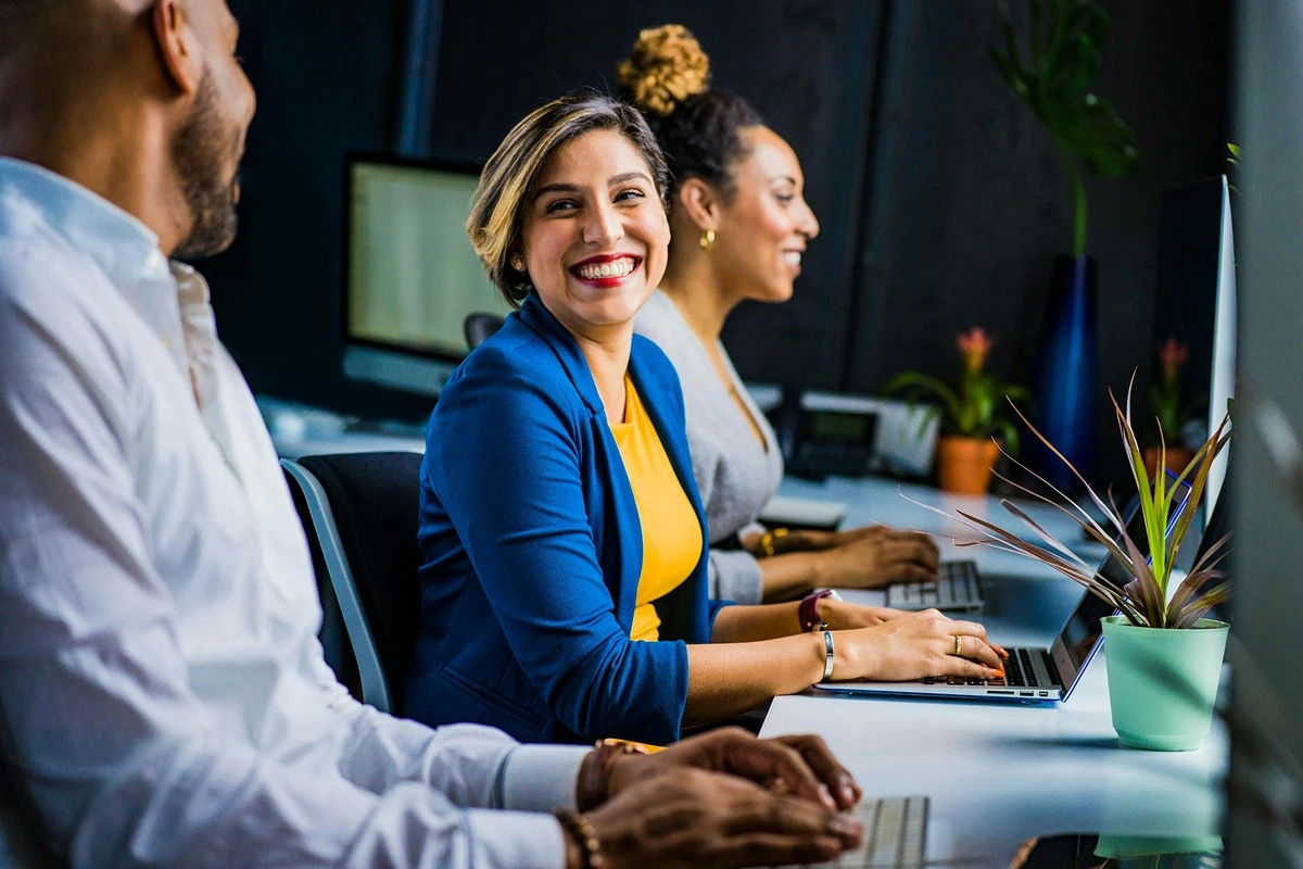professionals working and smiling at office desks.