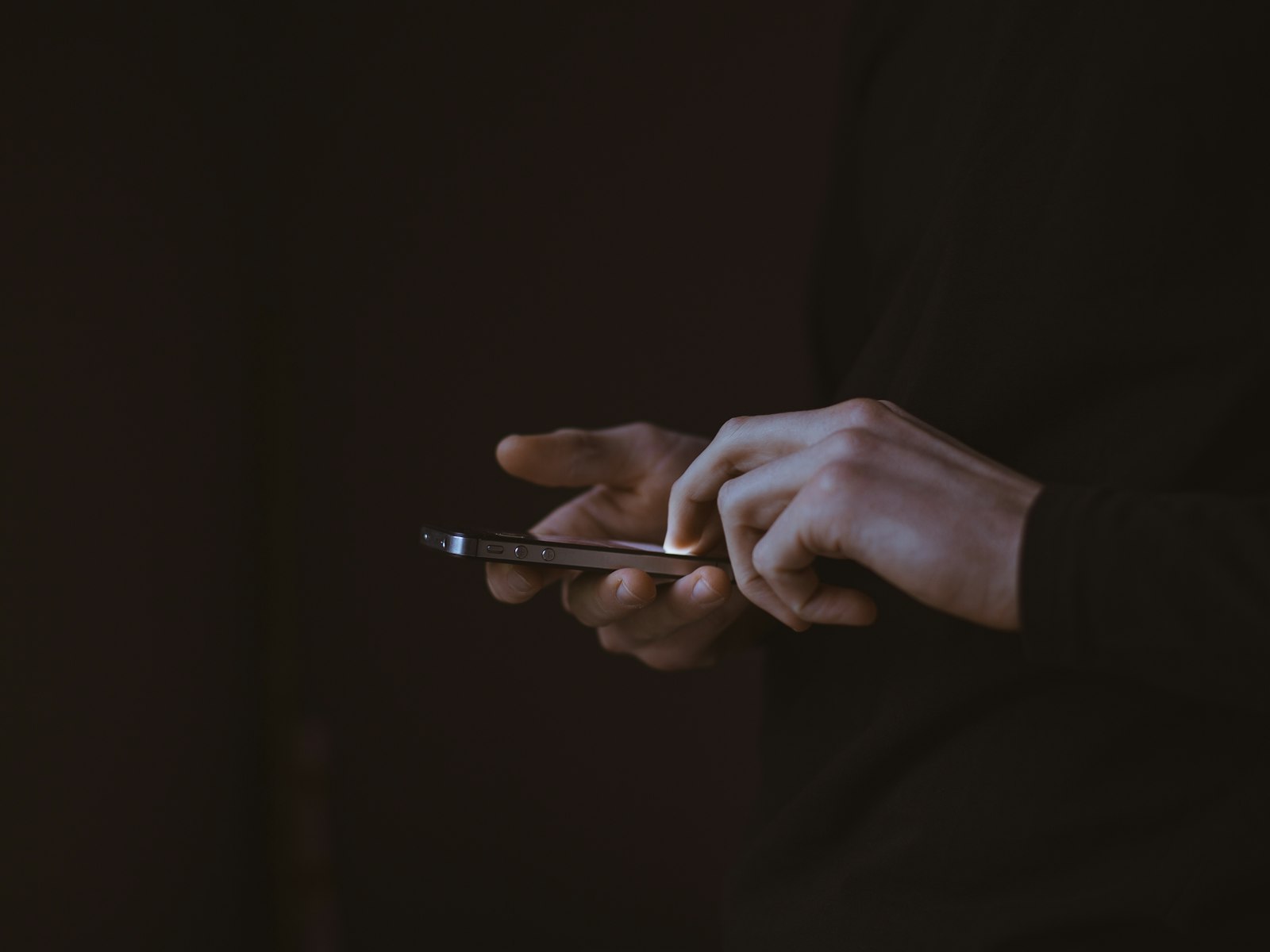 Hands holding a phone in a dark room while approving a payout