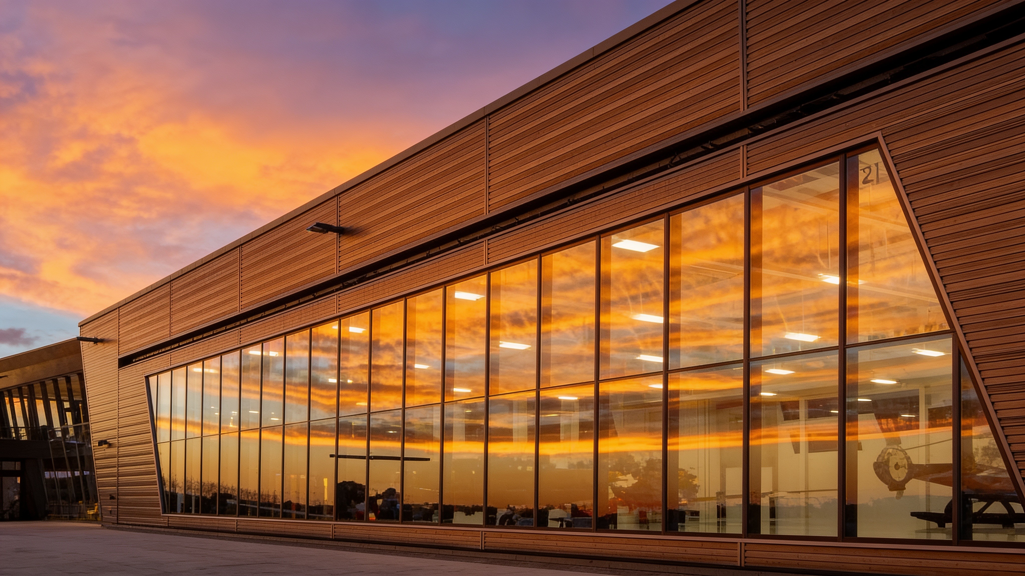 Glass-front hangar reflecting the sunset — local PowerLift support for the long haul