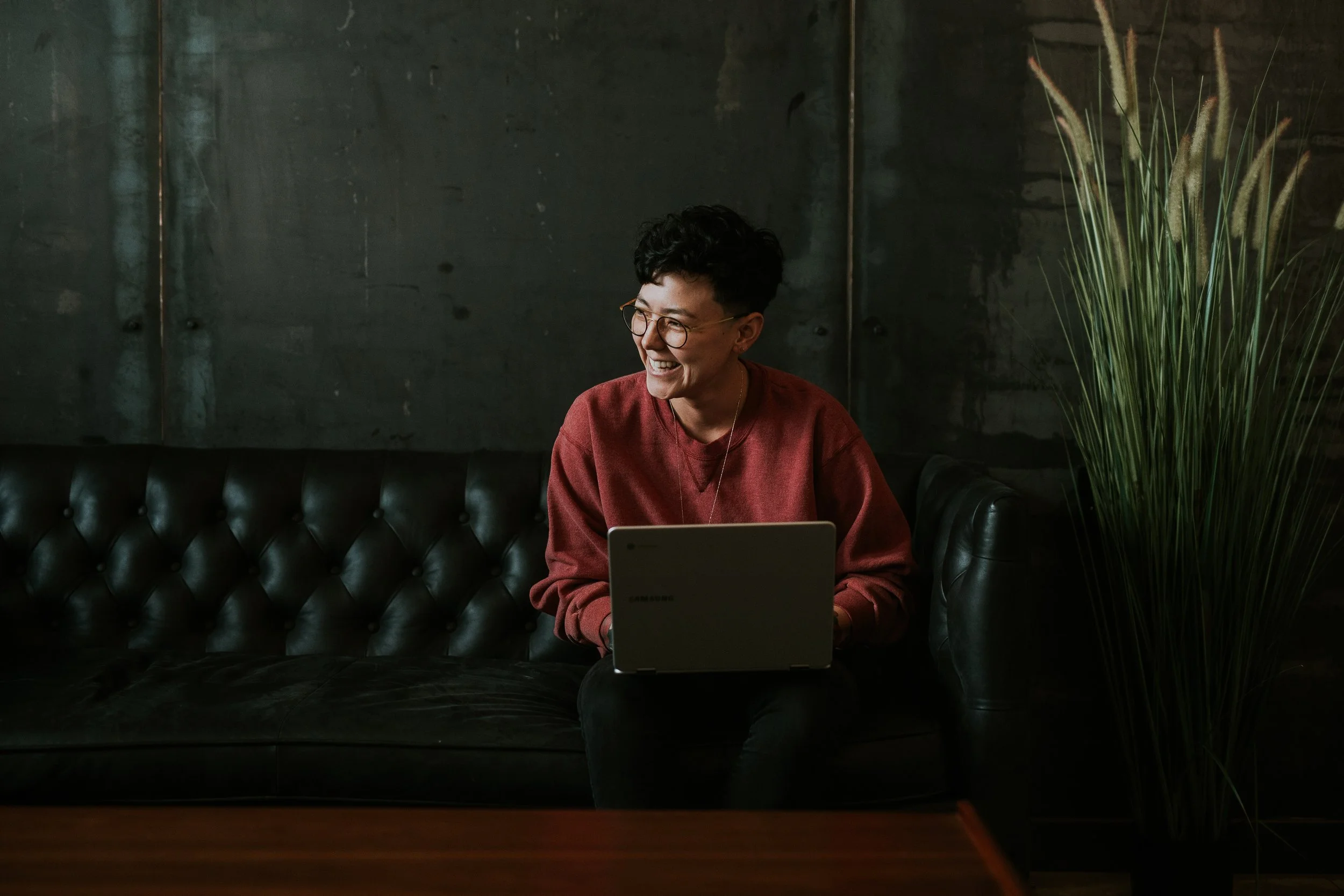 A person sits ont he couch, looking content as they join a virtual session