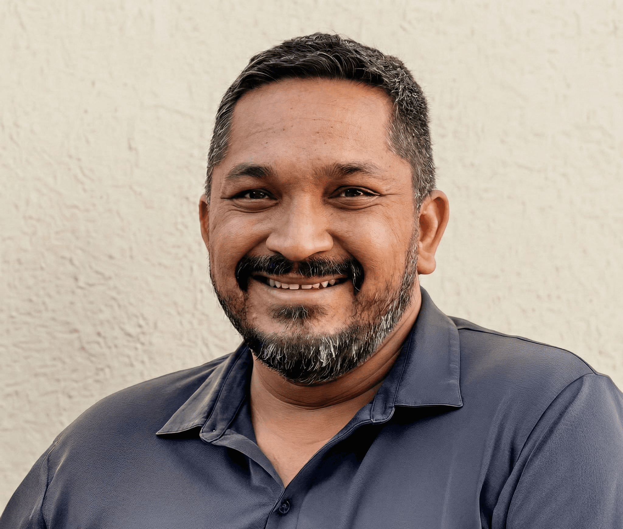 Young woman smiling gently in natural sunlight, with warm shadows cast across a minimal background.