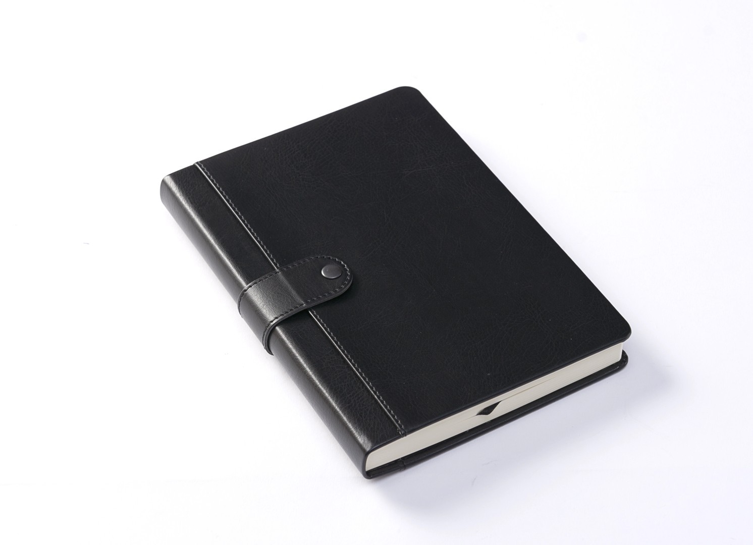 Angled view of closed black notebook secured by snap strap.