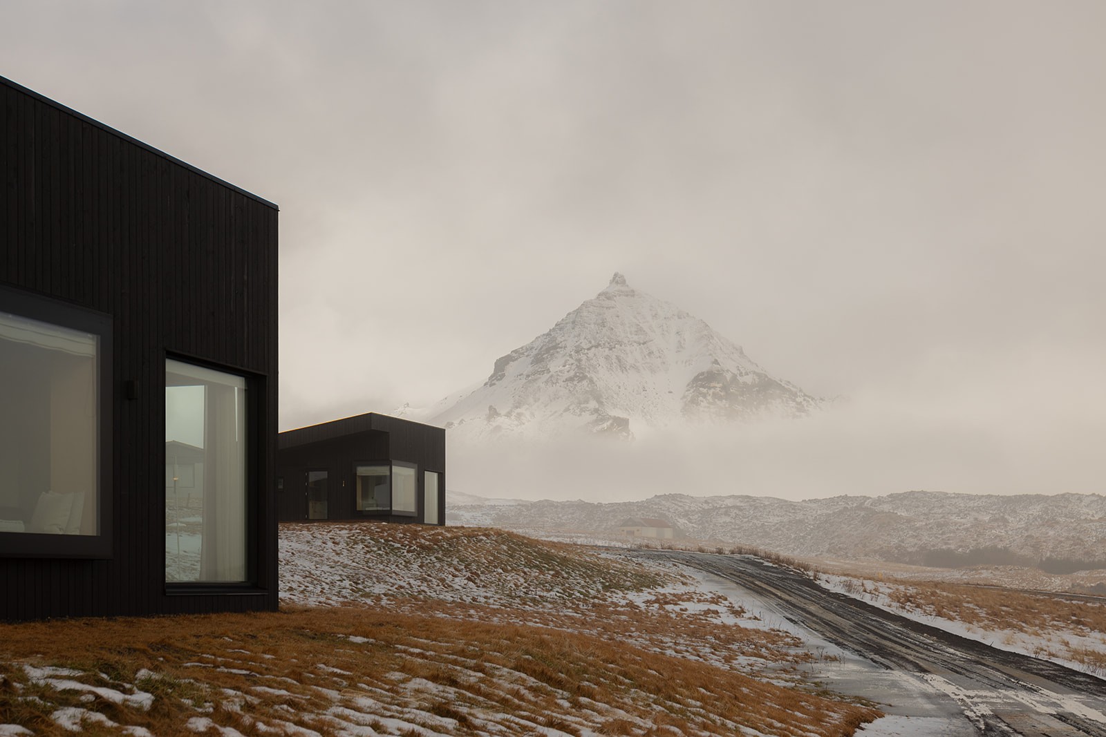 A snowy mountain in a mist and two houses from Peninsula Suites in Iceland