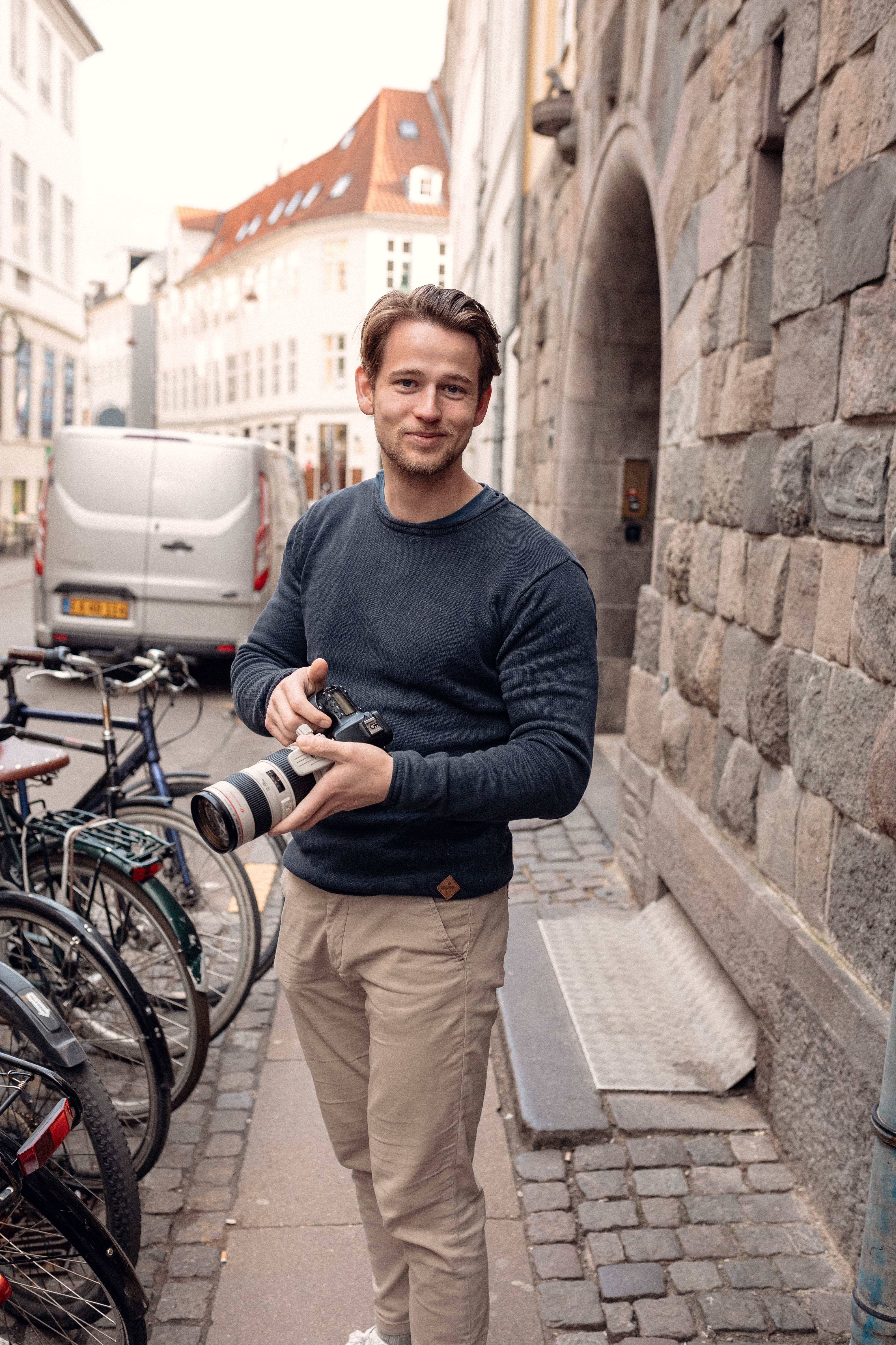 Sebastian Kolter, founder af Invisu, fotograferet i Københavns gader med kamera i hånden – portræt brugt til at fremhæve den personlige tilgang bag virksomhedens contentproduktion.