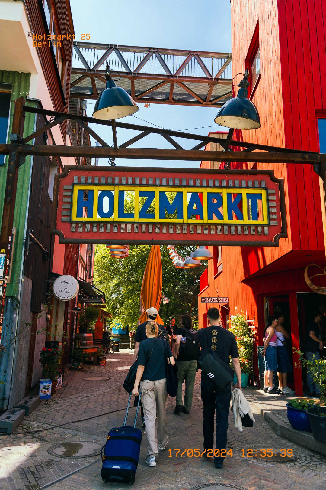 Passants entrant sous l'enseigne colorée Holzmarkt.  