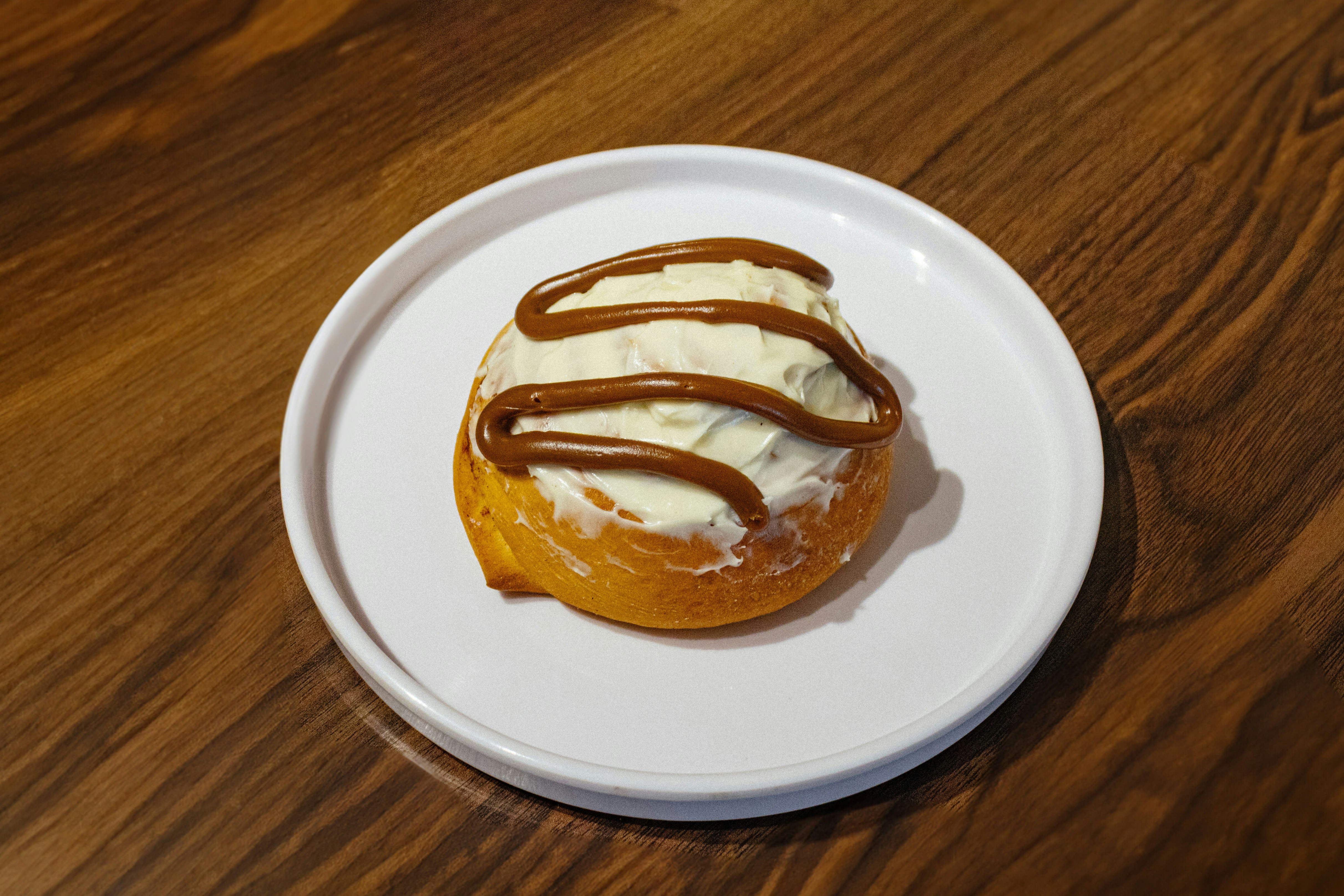 A donut on a white plate on a wooden table