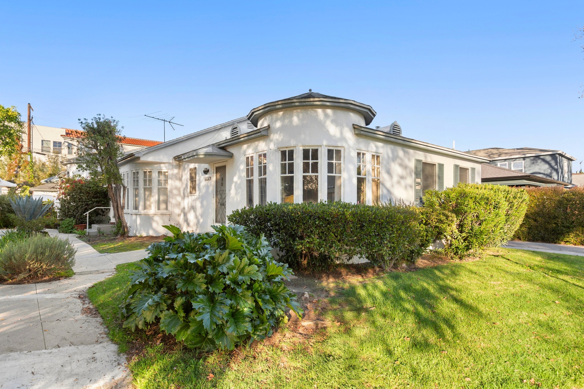 Close-up exterior angle showcasing original detailing and mature greenery at the triplex located at 10651 Whipple.