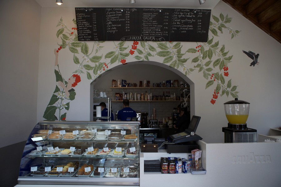 A photo from a cafeteria that has a wall painted with green leaves and red flowers.