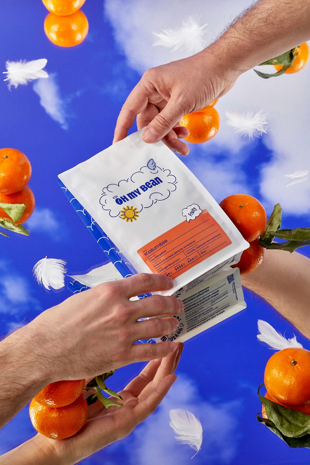 Oh My Bean Colombia coffee being passed between two hands, surrounded by oranges