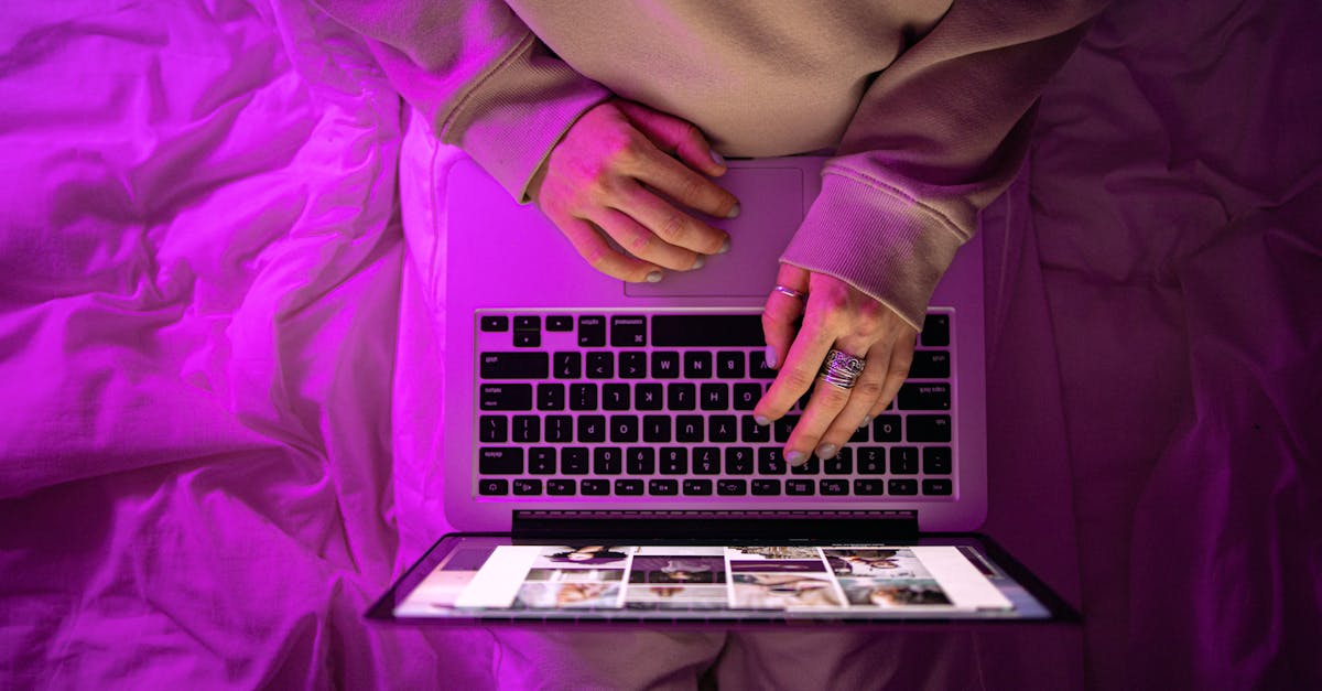 Top view of unrecognizable person using laptop with neon purple lighting, creating a vibrant high-te