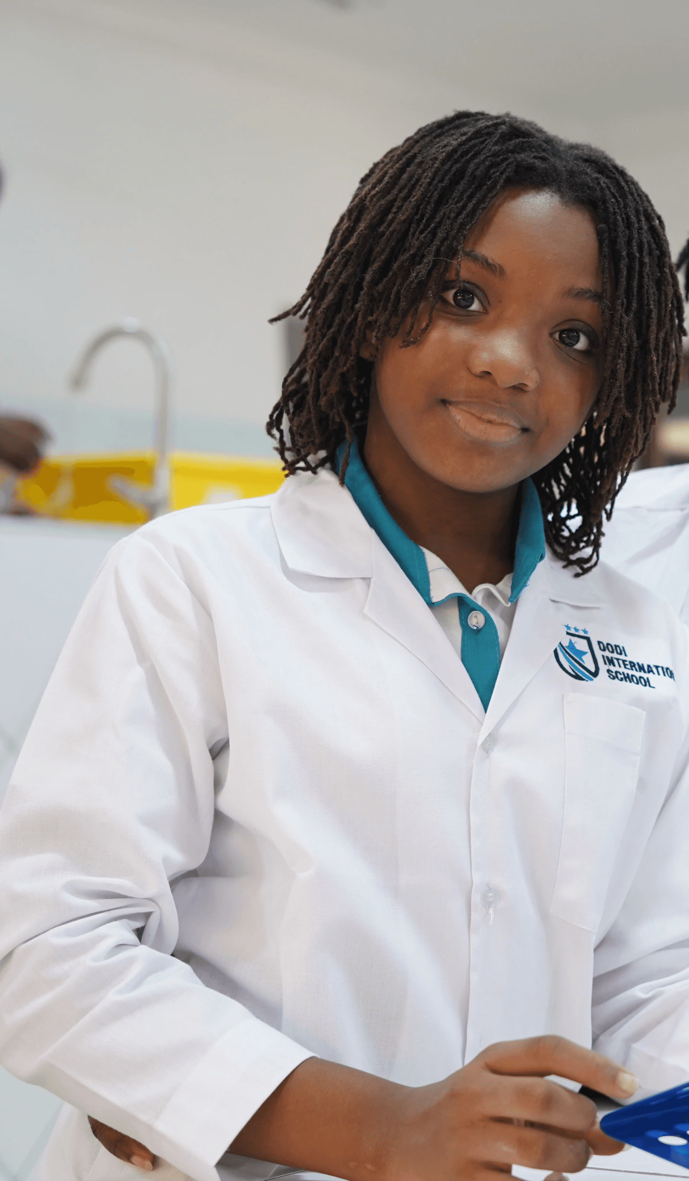 Two women in lab coats smile at the camera, standing near laboratory equipment in a bright, modern setting.
