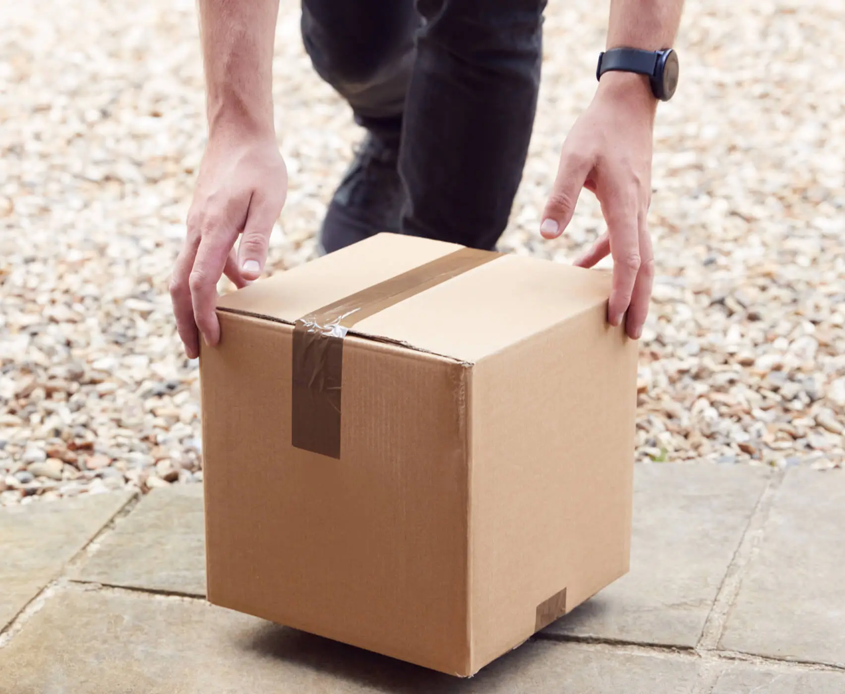 Person placing a cardboard delivery box on doorstep